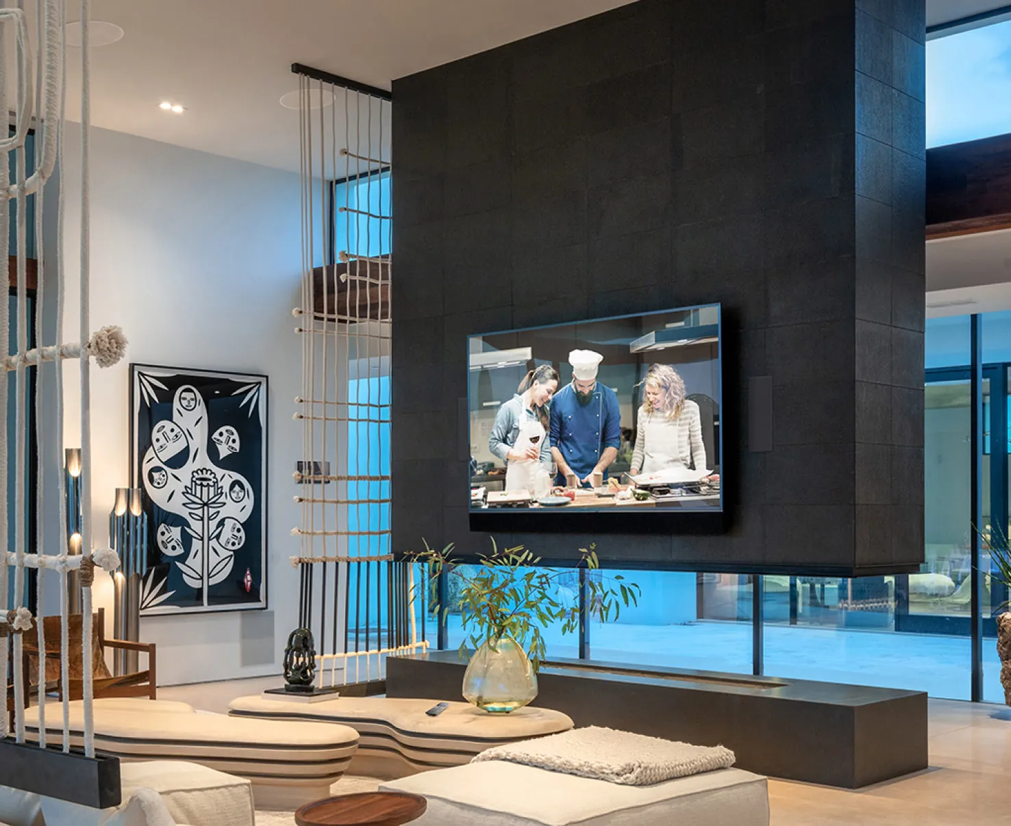 A living room with a large screen on a dark stone wall